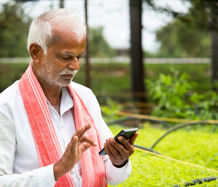 Indian,Farmer,Busy,Using,Mobile,Phone,While,Sitting,In,Between